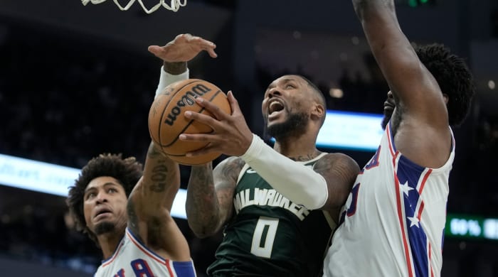 Bucks guard Damian Lillard shoots between 76ers players Kelly Oubre Jr. and Joel Embiid during the second half of a game.